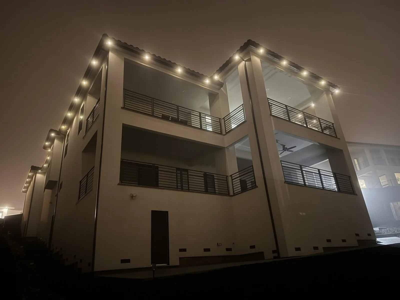 Modern building with warm LED accent lights along roofline and architectural features at night
